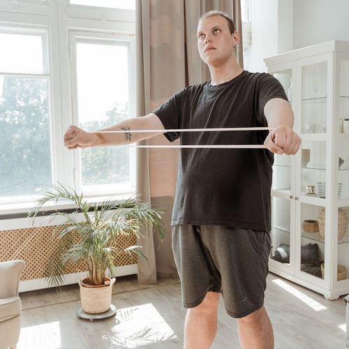 Man stretching by a window in his home.